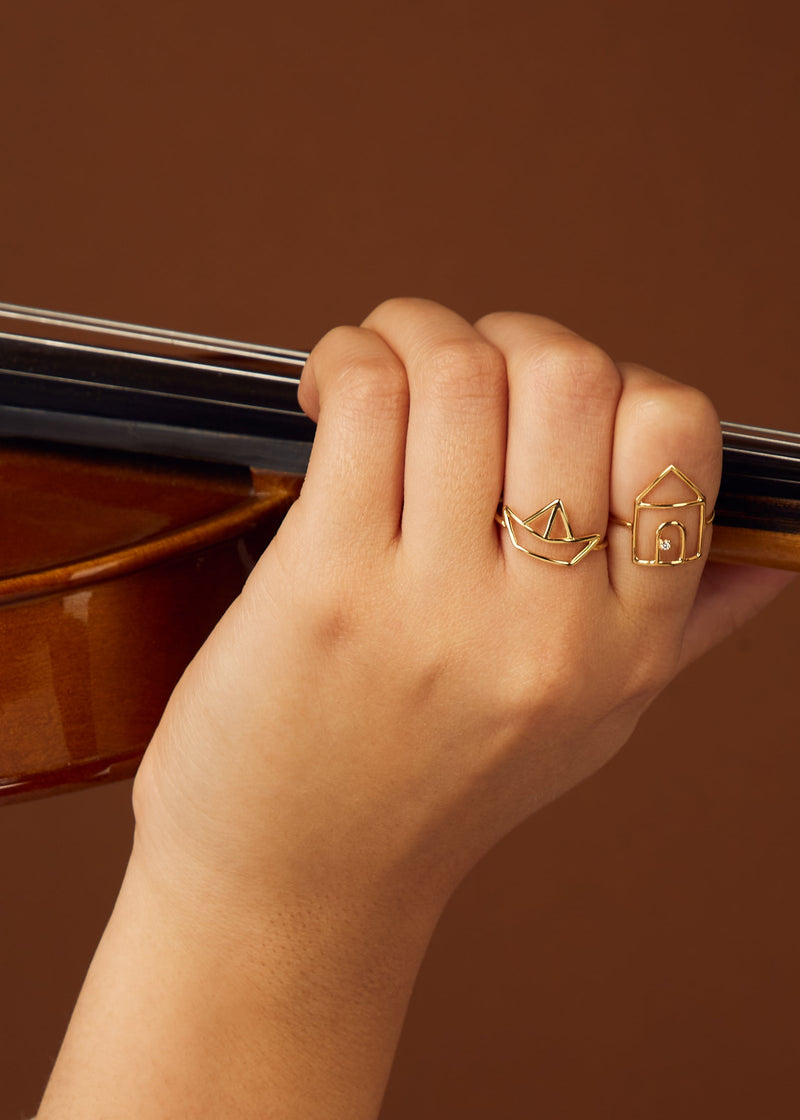 House and little boat shaped gold rings on woman's hand