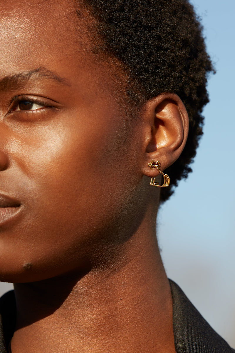 Seated cat shaped earring worn by woman