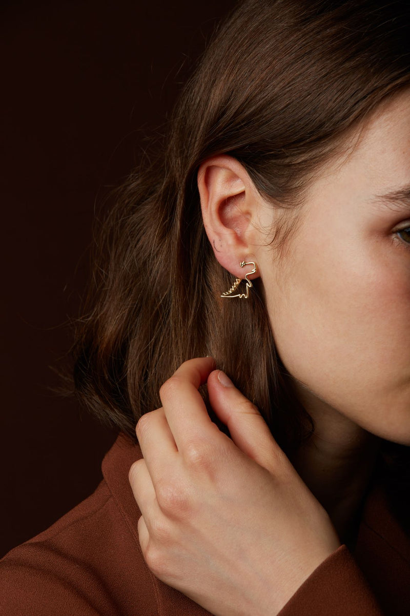 Gold dinosaur shaped earring worn by model