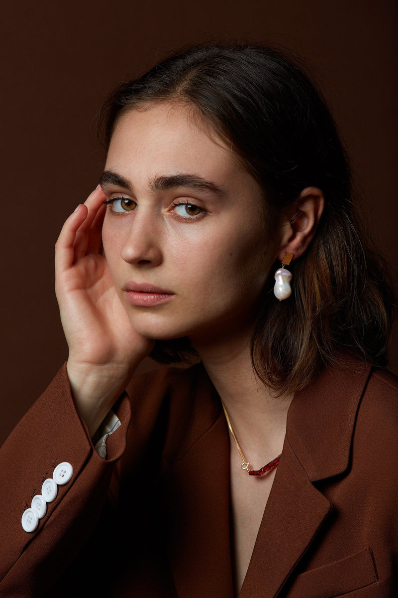 Model wearing gold earring with fresh water baroque pearl