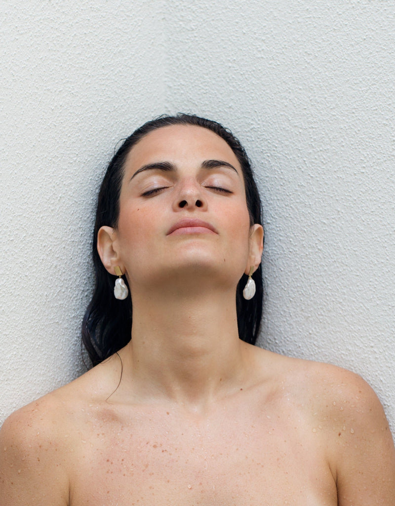 Model wearing gold earrings with fresh water baroque pearls