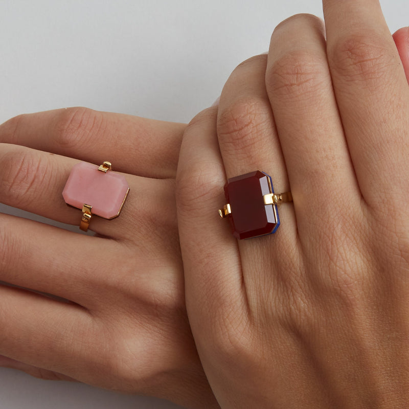 Gold turning ring with carnelian and pink oapl stones on woman's hands