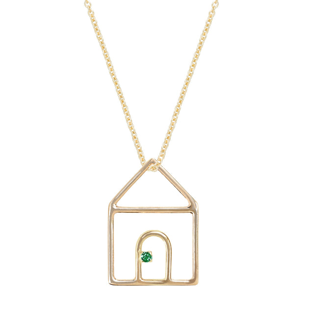 Gold chain necklace with house shaped pendant and small emerald