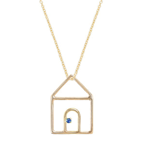 Gold chain necklace with house shaped pendant and small blue sapphire