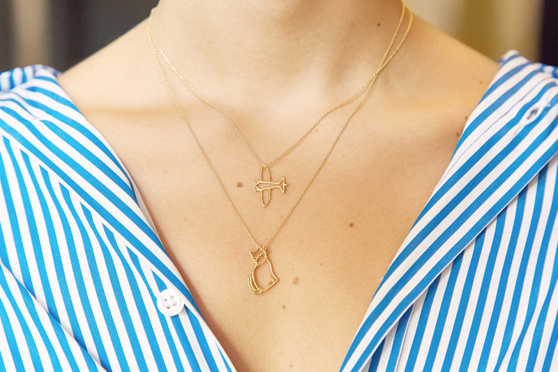 Gold chain necklace with seated cat shaped pendant worn by model