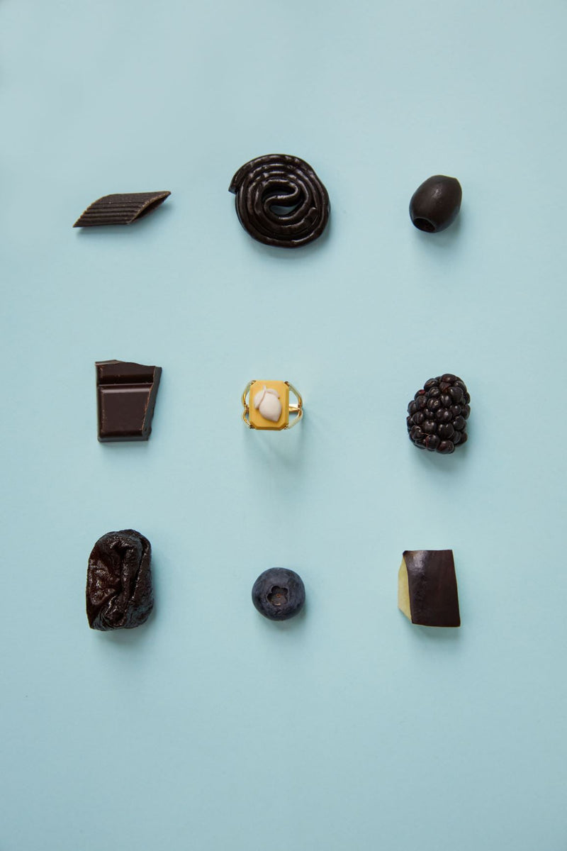 Composition with black food and gold ring with lemon shaped porcelain cameo