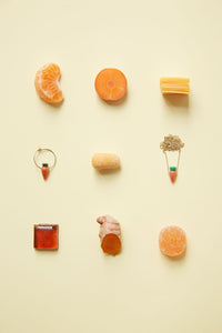 Jewelry and food composition with coral carrot earring and gold necklace
