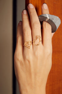 Hand wearing a gold striped heart shaped ring