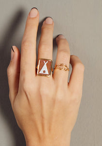 Hand wearing a tepee cameo on shell gold ring and a crocodile shaped gold ring