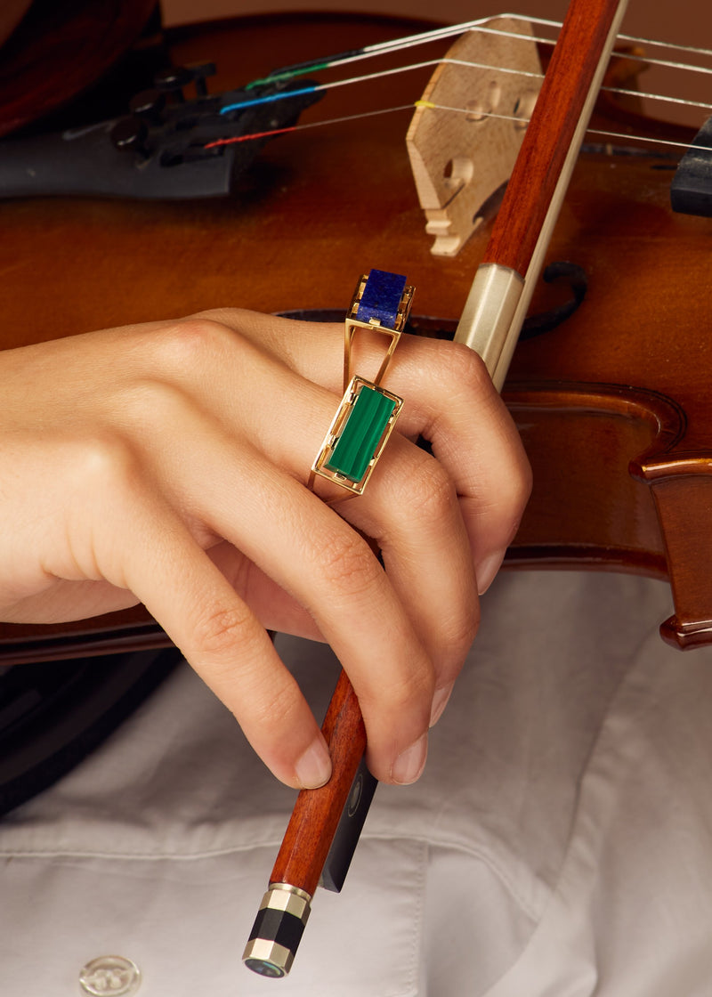 Hand holding violin with gold rings with malachite and lapis lazuli stones