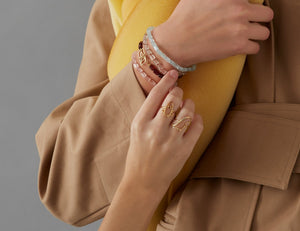 Model wearing beads bracelets and gold rings