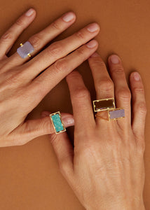Hands weraing gold rings with various stone sin rectangular cut