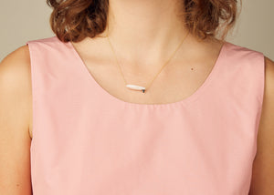 Gold chain necklace with surf shaped white coral pendant on model