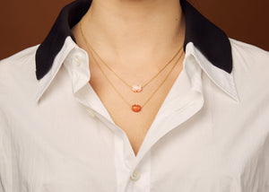 Gold chain necklace with mini red crab shaped coral worn by model