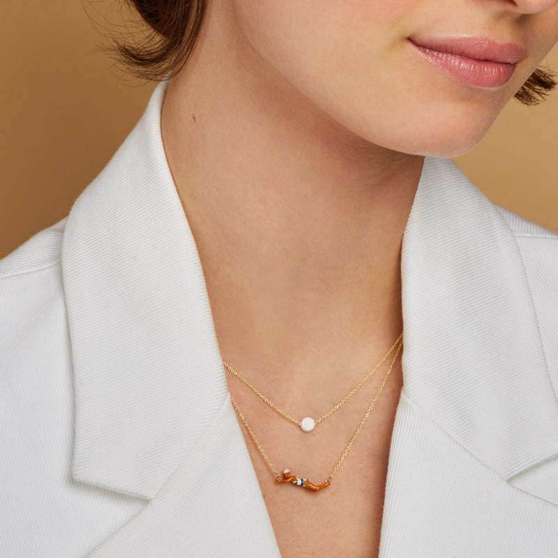 Gold chain necklace with a full moon shaped white coral worn by model