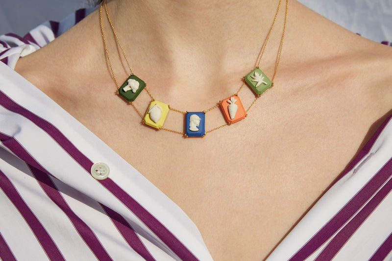 Gold chain necklace with multiple colored porcelai cameo pendants worn by model