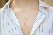 Load image into Gallery viewer, Model wearing gold chain necklaces with small camera and dinosaur pendants with emerald
