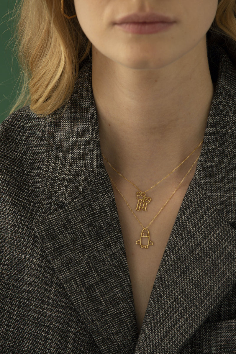 Gold chain necklace with space shuttle shaped pendant worn by model