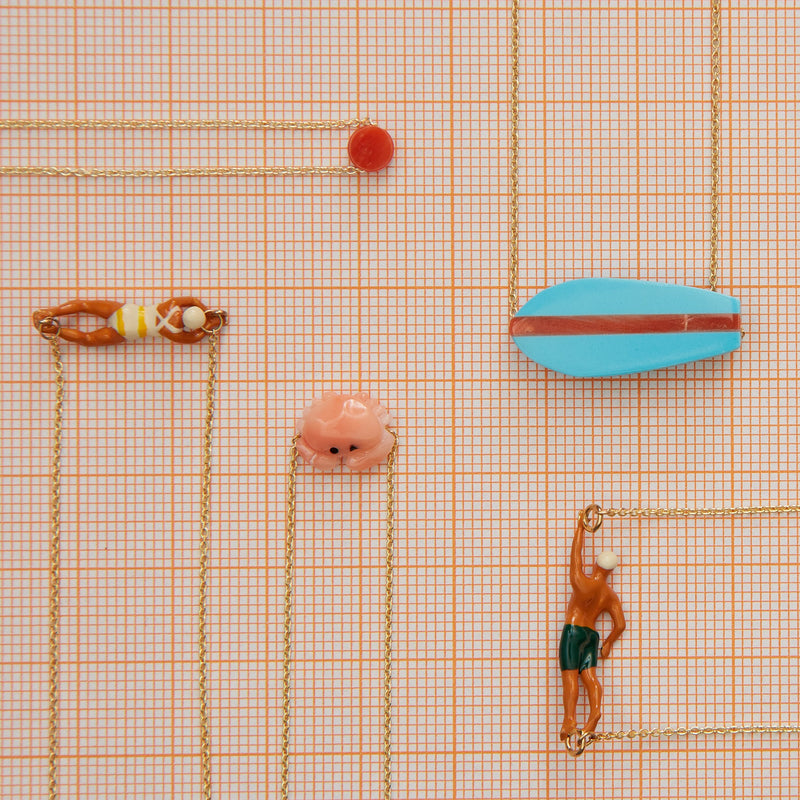 Jewelry composition with gold necklaces with surf, swimmer, crab shaped pendants