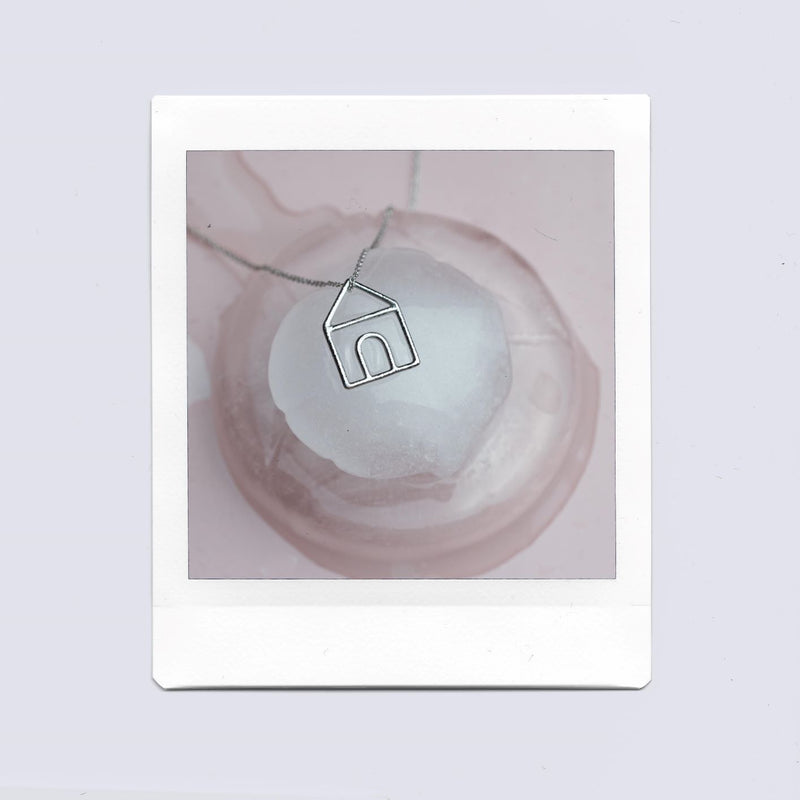 White gold chain necklace with house shaped pendant on ice cubes