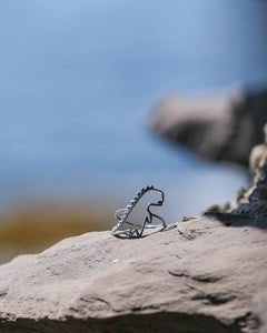 Dinosaur shaped white gold ring on a rock