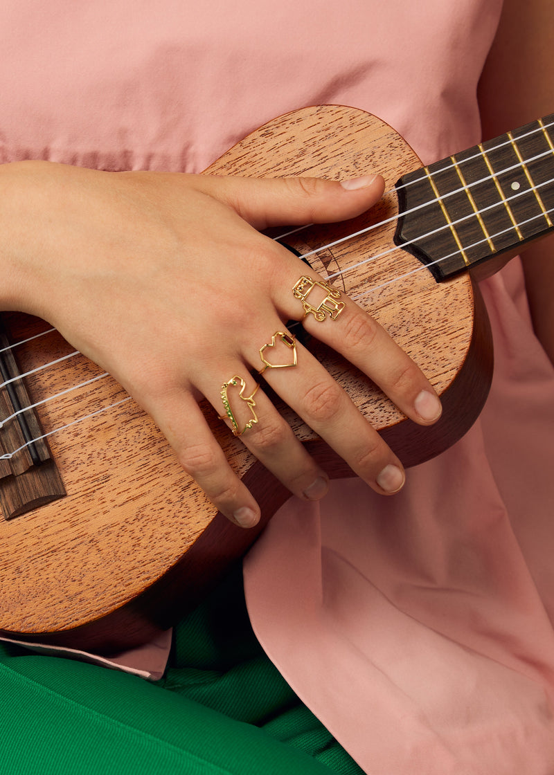 Gold robot shaped ring with blue sapphires as eyes worn by model playing ukulele