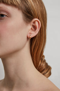 Model wearing a mini gold hoop earring