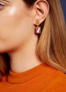 Woman wearing gold earrings with eggplant cameos made in porcelain