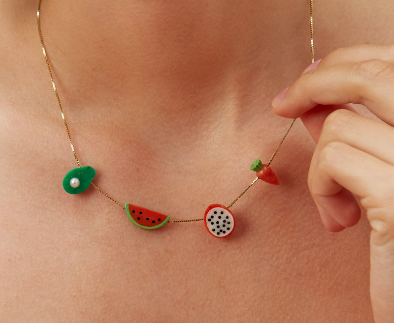 Woman wearing a gold chain necklace with coral and turquoise fruit