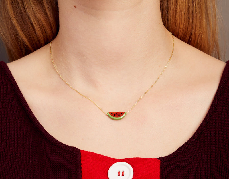 Woman wearing a gold chain necklace with a watermelon slice in red coral and oxidized turquoise